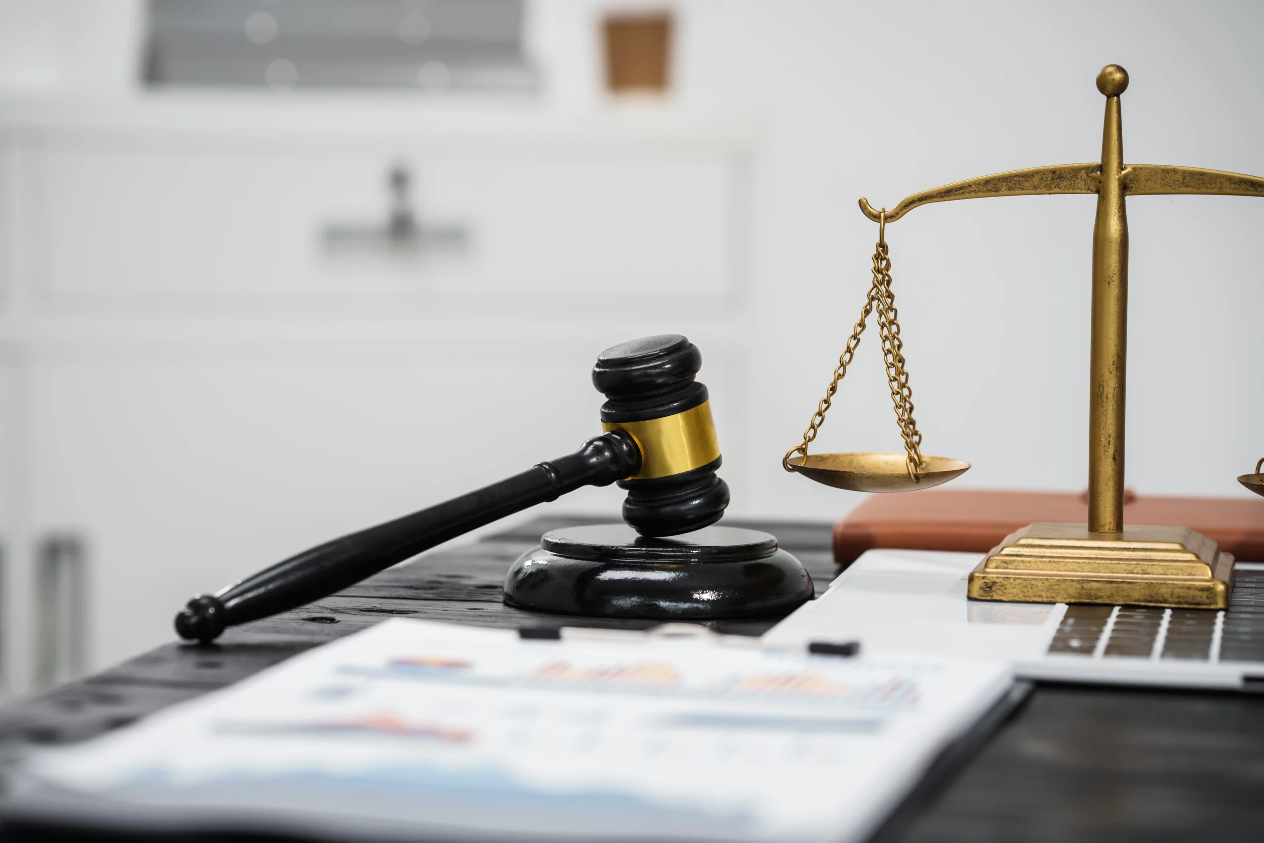 Gavel and brass scales of justice on a dark table with blurred financial charts, symbolizing legal decision-making in bankruptcy cases.