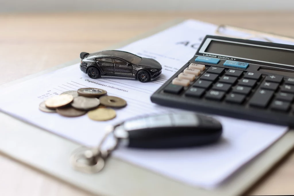 Miniature car, calculator, coins, and car keys on financial documents, illustrating options for keeping a vehicle during Chapter 7 bankruptcy in Maryland.